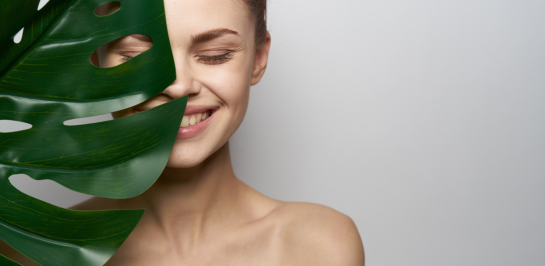 make-your-own-at-home-beauty-masks-smiling-woman-with-great-skin-holding-a-leaf