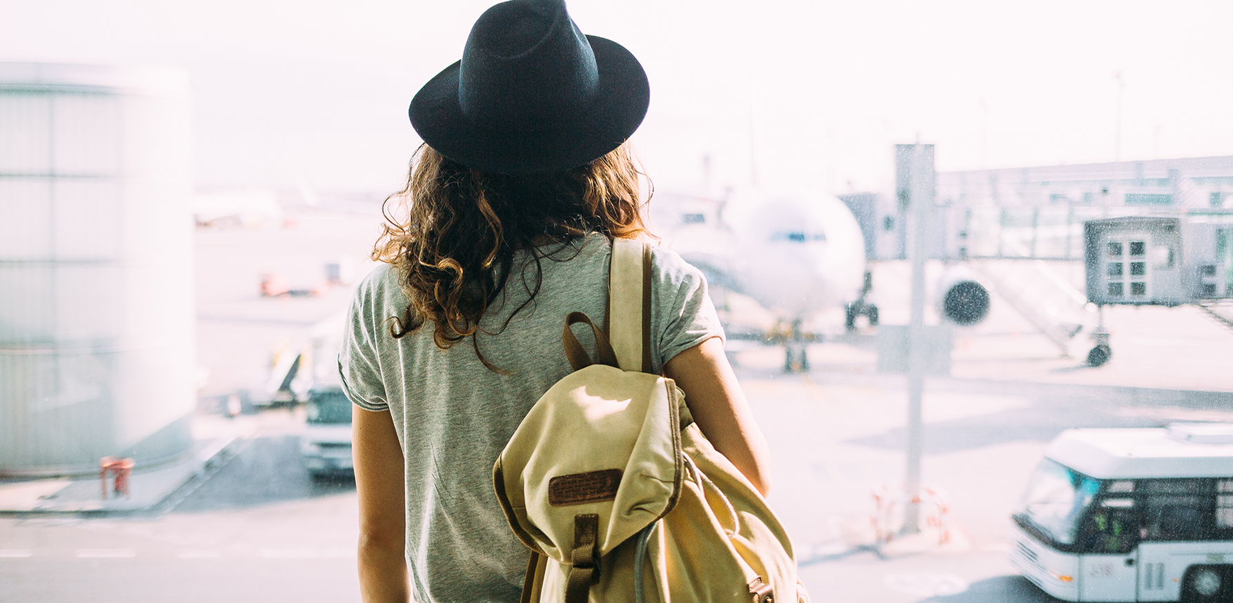 beauty-product-travel-essentials-woman-holding-bag-looking-at-plane