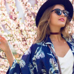 fashion-for-different0body-types-woman-in-blue-kimono-tunic-and-black-hat-against-cherry-blossoms-fashio
